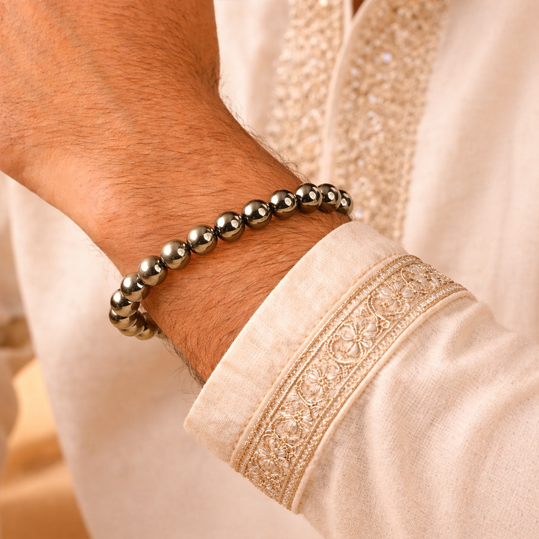 Close-up of a person wearing a beaded bracelet on a beige garment with intricate patterns.Fame & Fortune Attract: Golden Pyrite Bracelet - Abhimantrit & Certified