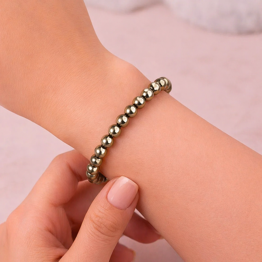 Gold beaded bracelet on a wrist with a plain backgroundFame & Fortune Attract: Golden Pyrite Bracelet - Abhimantrit & Certified