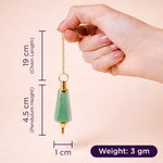 Hand holding a green pendulum with measurements on a beige background