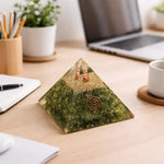 Decorative pyramid on a desk with laptop, notebook, and cup in the background