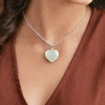 Necklace with a heart-shaped pendant worn by a person in a brown top
