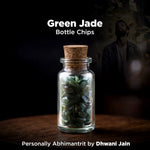 Glass bottle with cork lid containing green jade chips on a dark background