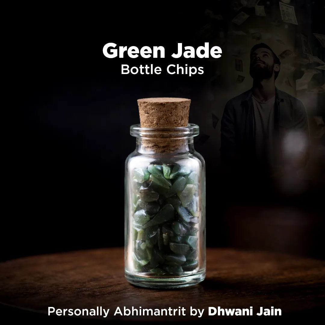 Glass bottle with cork lid containing green jade chips on a dark background