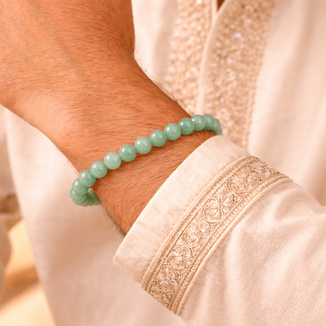 Green beaded bracelet on a wrist with a beige embroidered sleeve