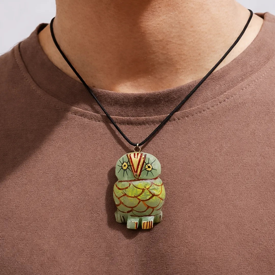 Person wearing a necklace with an owl-shaped pendant on a plain background