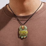 Person wearing a necklace with an owl-shaped pendant on a plain background