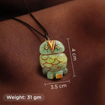 Green owl pendant with measurements on a brown background
