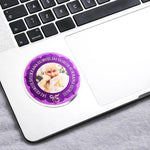 Round purple sticker with text and a photo on a laptop