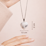 Heart-shaped marble pendant necklace with measurements on a pink background