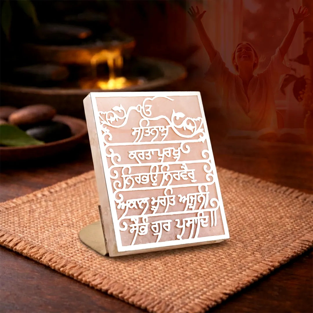 Decorative card with intricate designs and text on a stand, placed on a textured surface.