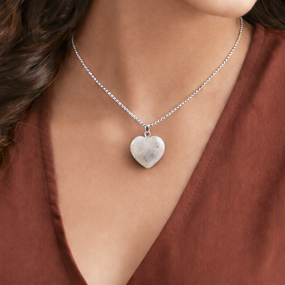 Heart-shaped pendant necklace on a person wearing a rust-colored top