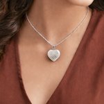 Heart-shaped pendant necklace on a person wearing a rust-colored top