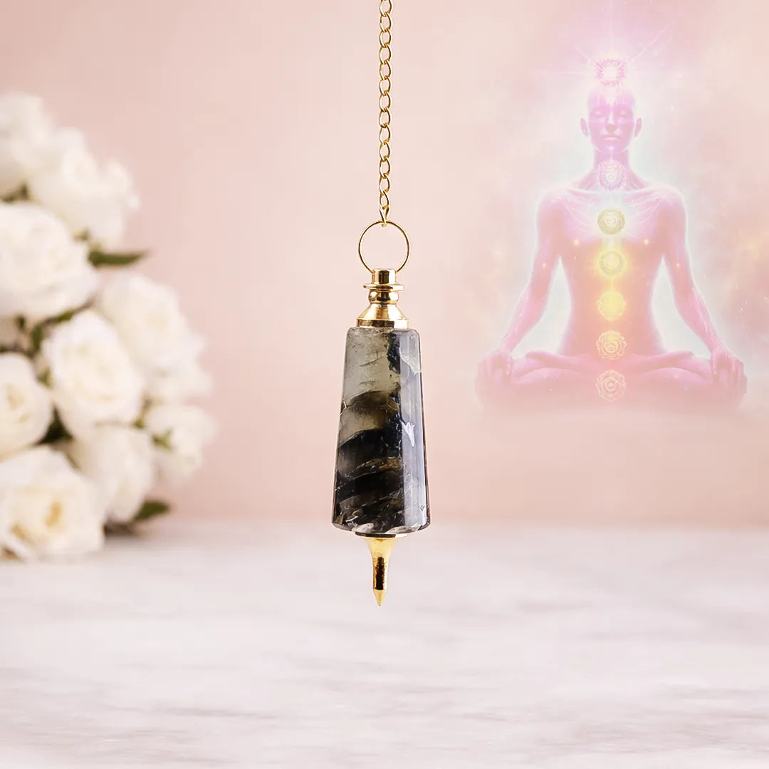 Decorative pendant with a blurred background of flowers and a statue.Labradorite Pendulum for Intuition, Protection & Dowsing - Abhimantrit