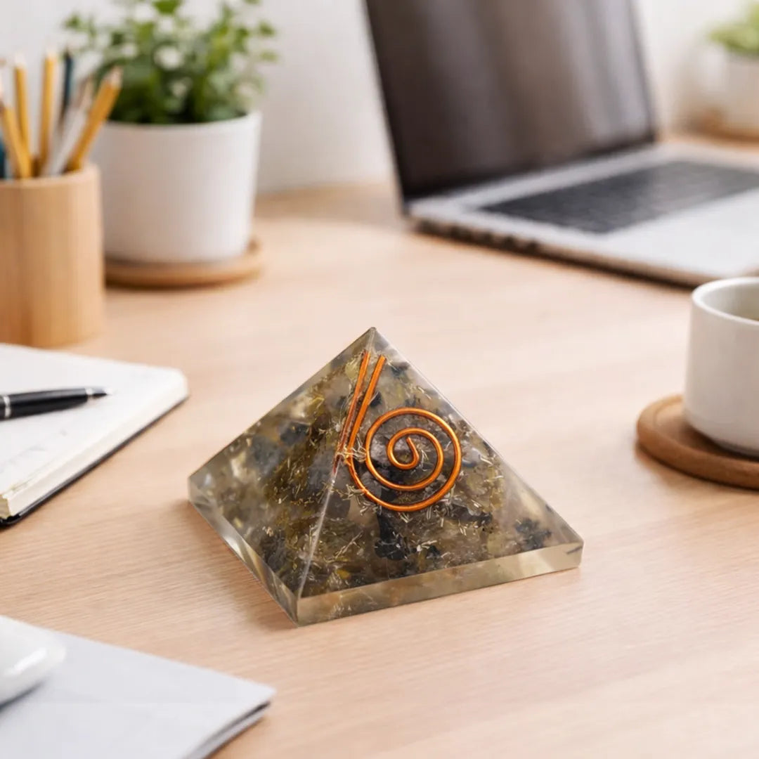 Pyramid-shaped decorative object with a spiral design on a desk with a laptop and office supplies.