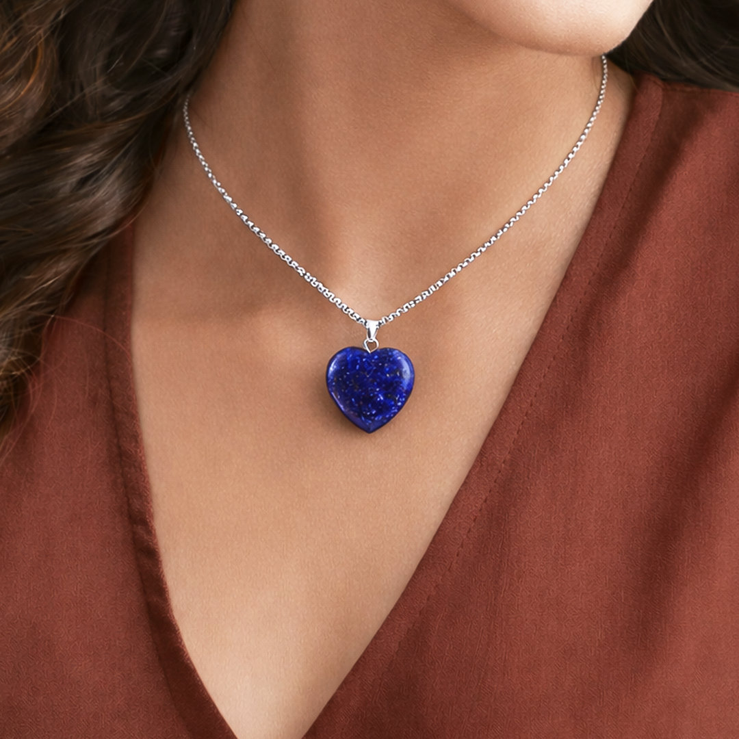 Necklace with a blue heart-shaped pendant worn by a person in a brown top.Lapis Lazuli Heart Pendant (Abhimantrit) for Clarity & Communication