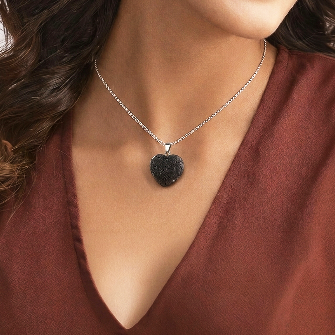Necklace with a black heart-shaped pendant worn by a person in a red garment.