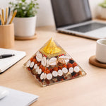 Decorative pyramid on a desk with laptop, notebook, and cup in the background