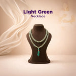 Light green necklace on a brown mannequin with a beige background