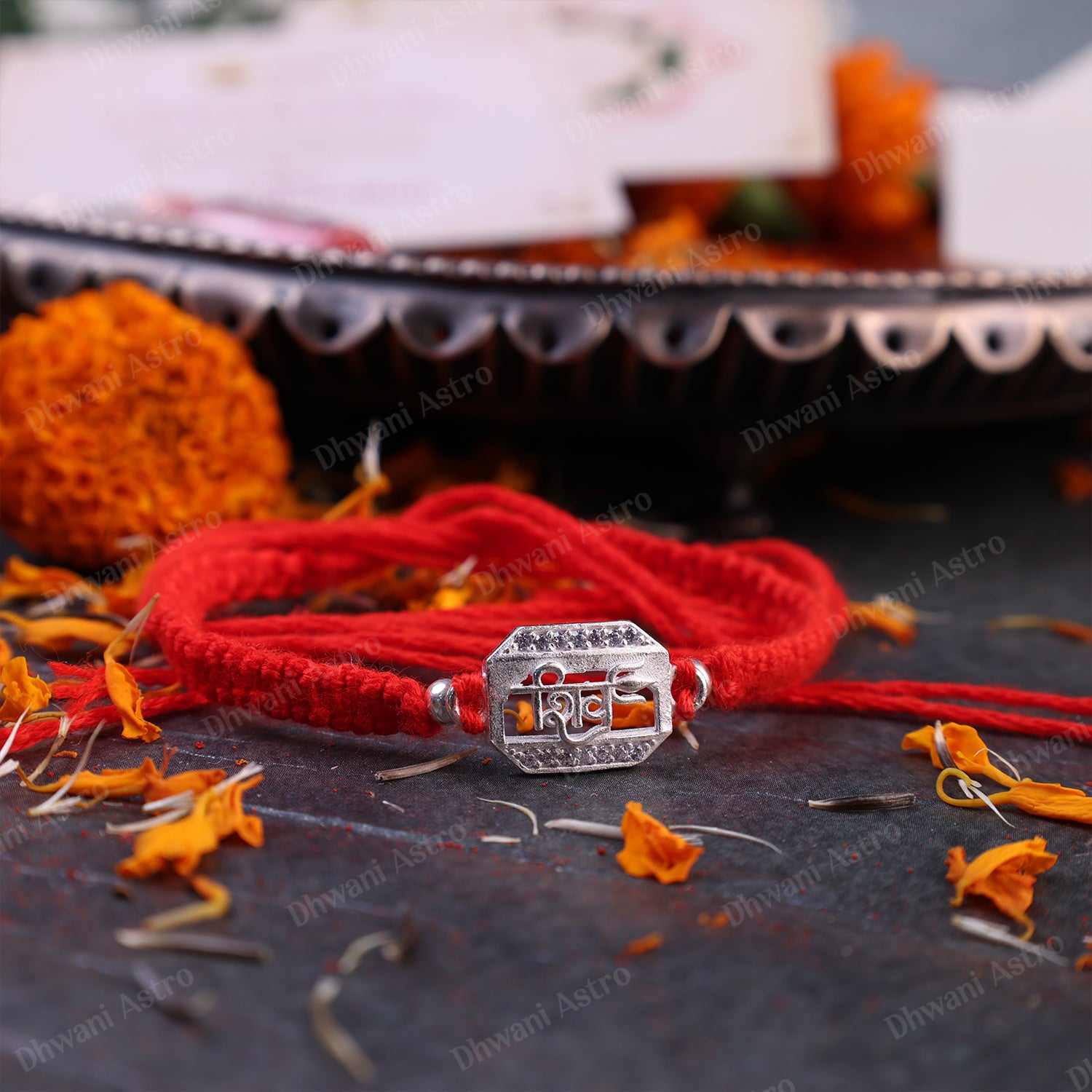 Elegant 925 Silver Shiv Rakhi displayed with marigold flowers, perfect for Raksha Bandhan gifting for brother.925 Sterling Silver Shiv Rakhi | Handmade Red Thread Raksha Bandhan Bracelet for Brother