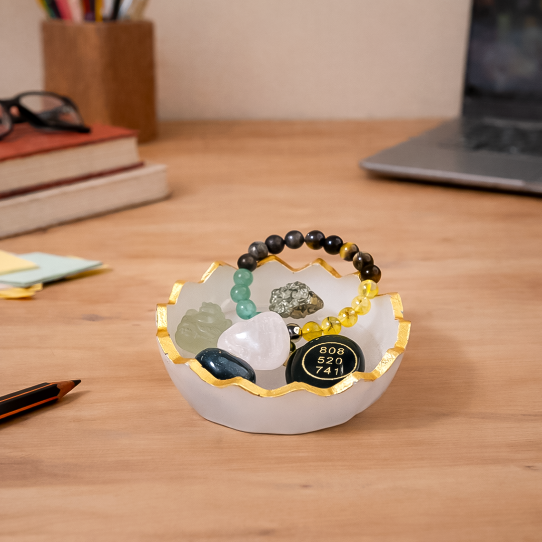 Decorative bowl with stones and a bracelet on a wooden desk