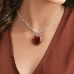 Heart-shaped pendant necklace on a person wearing a rust-colored top
