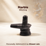 A black marble Shivling statue displayed on a light beige surface with a soft, warm background and text overlays reading 'Marble Shivling' and 'Personally Abhimanitrit by Dhwani Jain'.