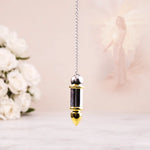Decorative pendant with gold and silver accents on a blurred floral background