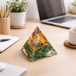 Pyramid-shaped decorative object on a desk with a laptop and office supplies in the background