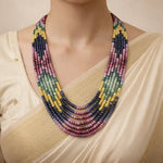 Multicolored beaded necklace worn by a person in a beige outfit.