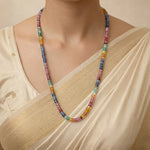 Multicolored beaded necklace worn by a person in a beige outfit.