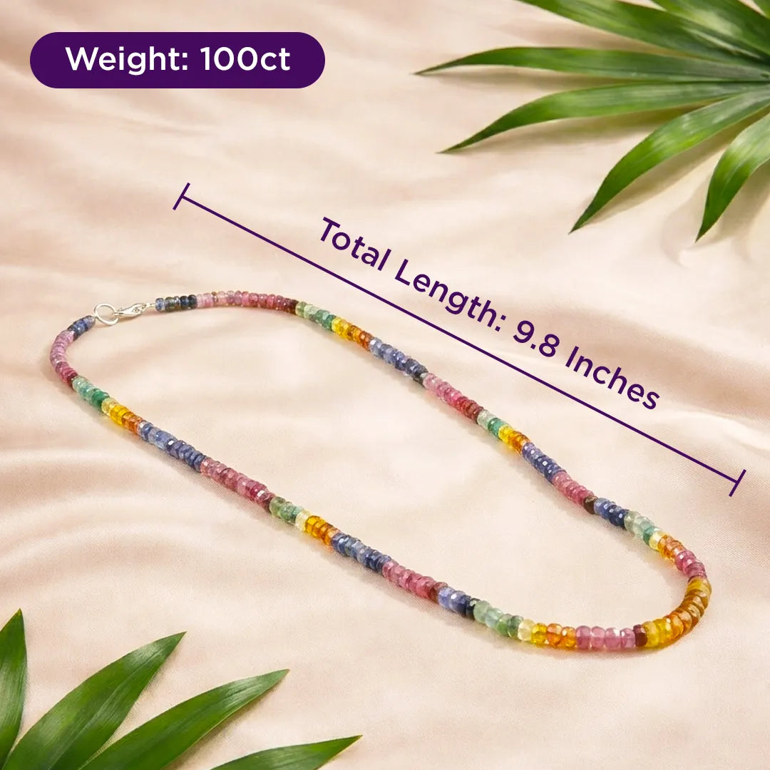 Colorful beaded necklace with measurements on a beige background with green leaves.