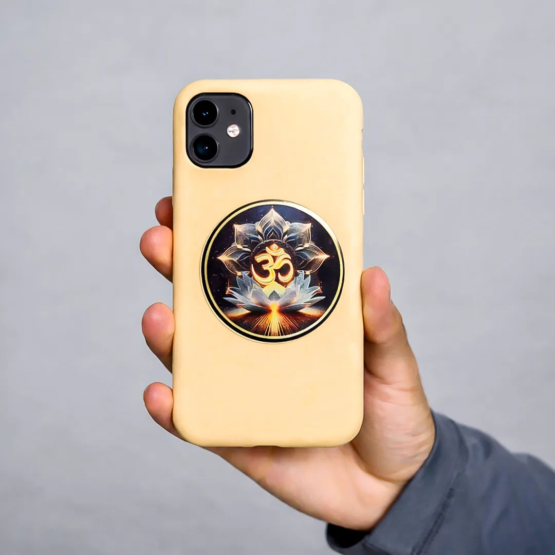 Hand holding a phone with a decorative case featuring an Om symbol on a gray background
