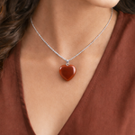 Heart-shaped pendant necklace on a person wearing a brown top