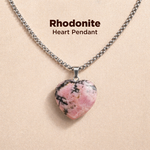 Heart-shaped rhodonite pendant on a chain against a beige background