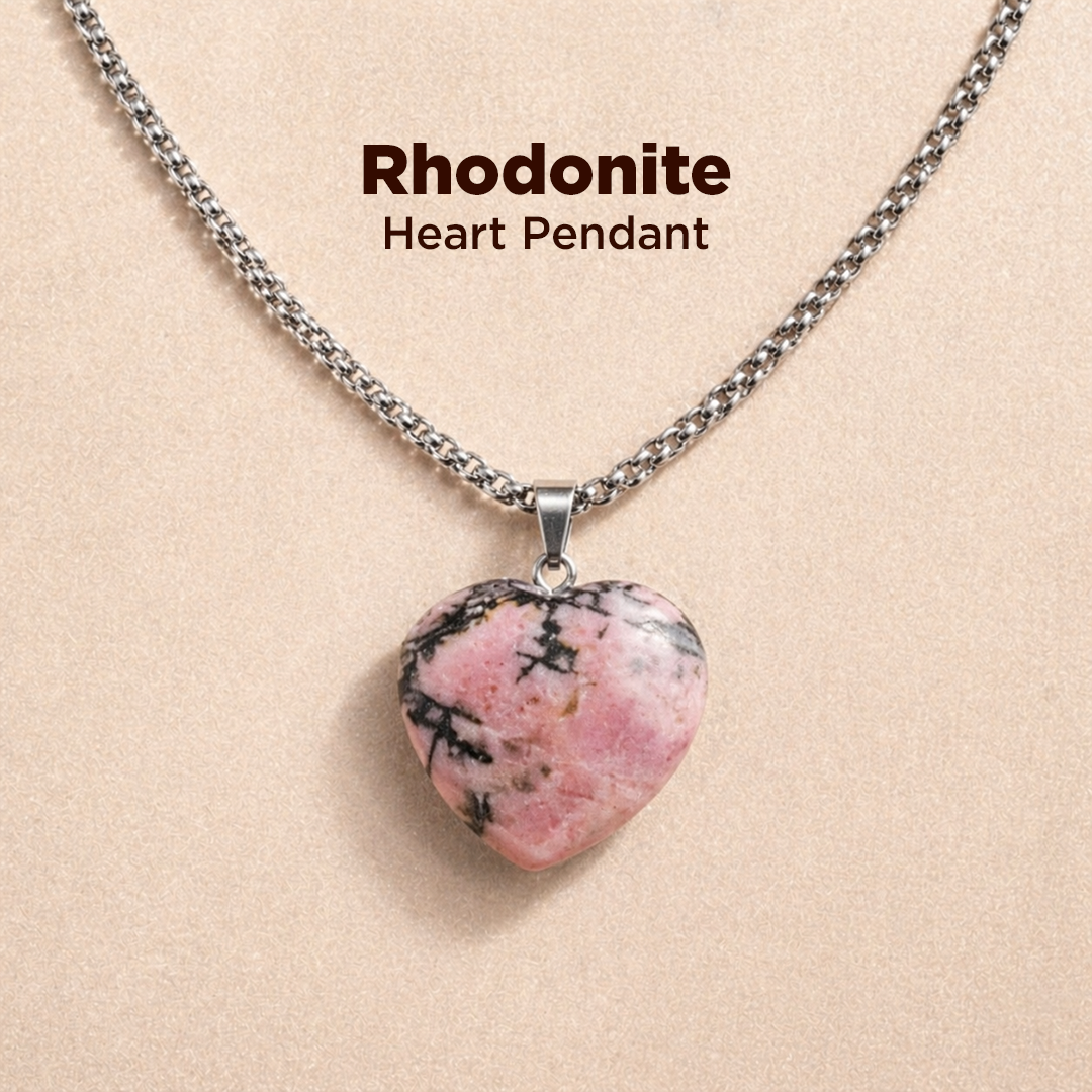 Heart-shaped rhodonite pendant on a chain against a beige background