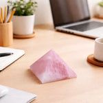 Pink crystal pyramid on a desk with laptop, notebook, and office supplies.