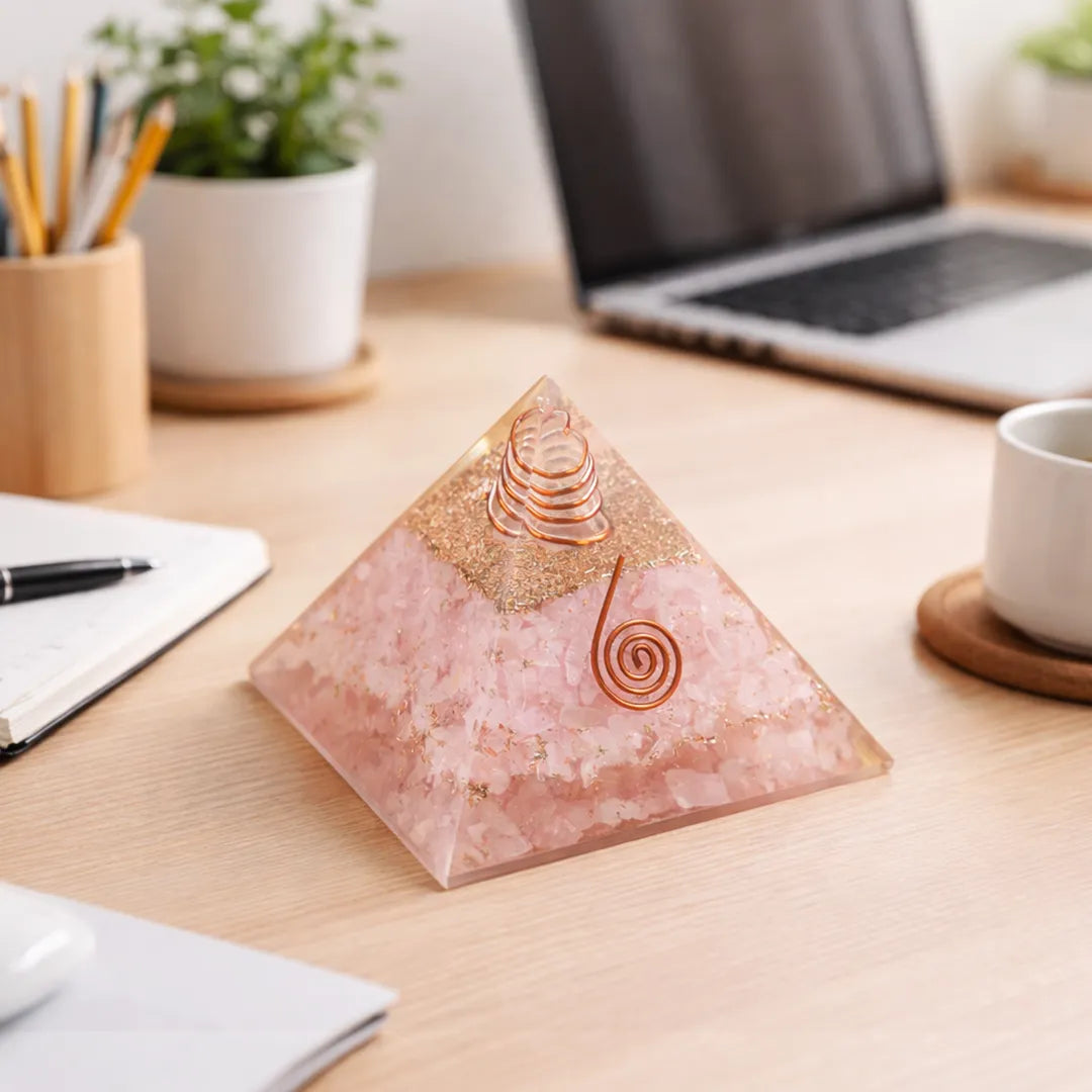 Decorative pyramid on a desk with laptop, notebook, and cup in the background