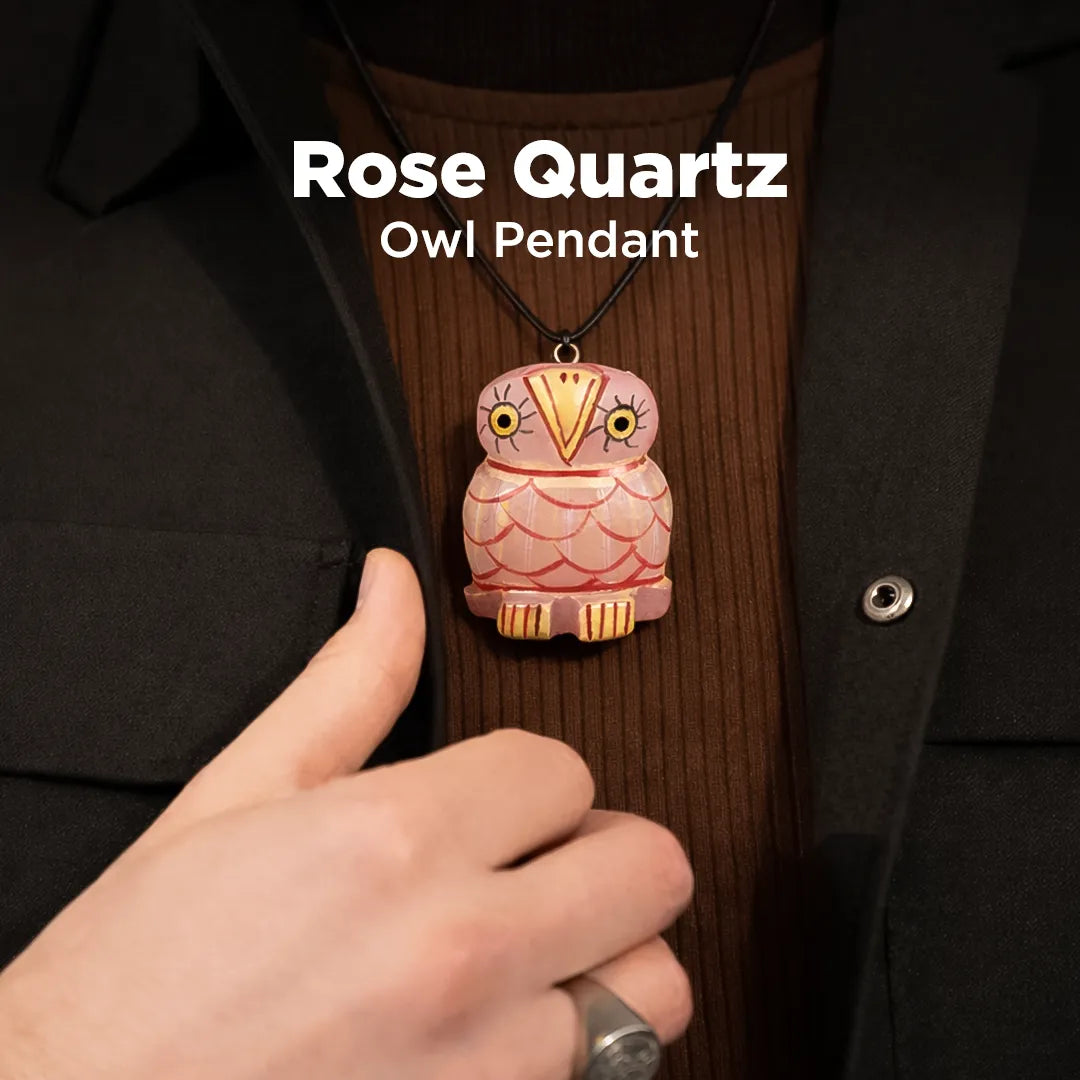 Rose Quartz Owl Pendant worn on a dark coat with a hand adjusting it.