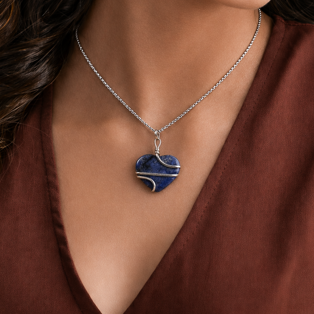 Necklace with a blue heart-shaped pendant worn by a person in a brown top.