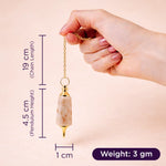 Hand holding a gold and beige pendant with measurements on a beige background