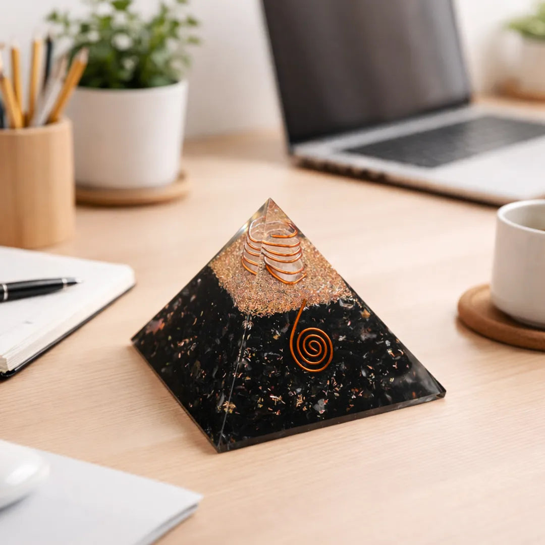 Decorative pyramid on a desk with laptop, notebook, and cup in the background