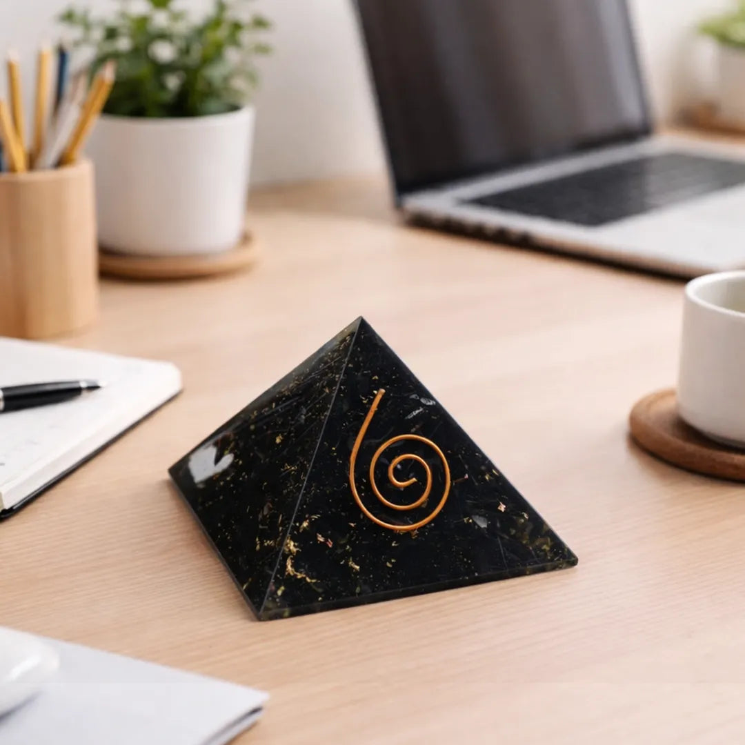 Black marble coaster with a gold spiral design on a wooden desk with office items.