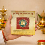Hand holding a gold-plated astrological tool with text and design, against a blurred background of traditional decor.
