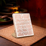 Decorative sign with engraved text on a wooden stand, placed on a textured surface.