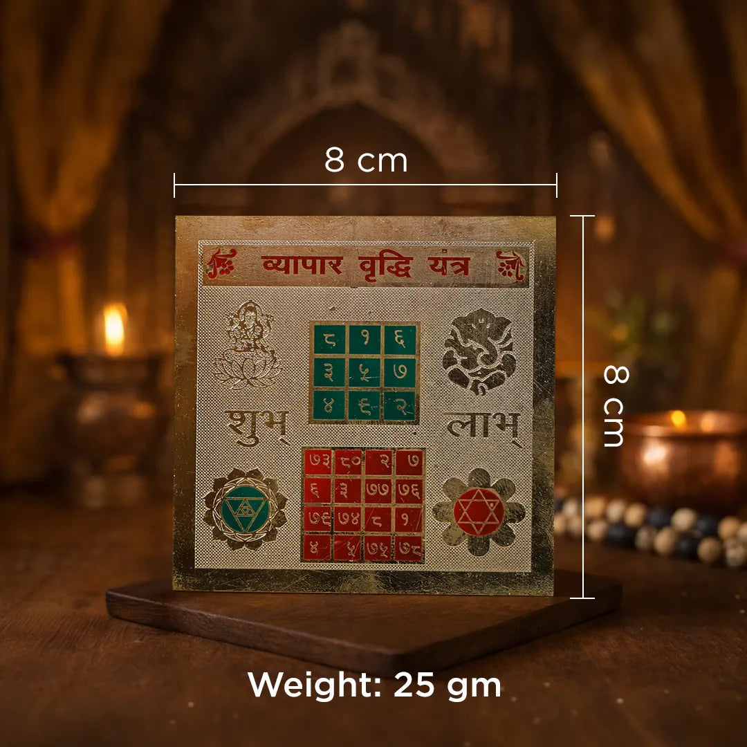 Decorative item with measurements and text on a wooden stand against a warm, blurred background.Vyapar Vridhi Yantra – 24K Gold Plated Yantra for Business Growth