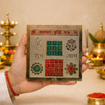Hand holding a decorative card with symbols and text against a blurred background of religious items.