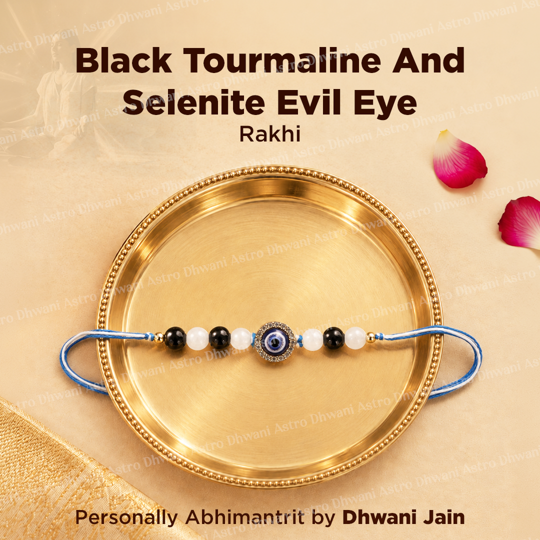 A black and white beaded evil eye rakhi with a blue cord, displayed on a gold-colored brass plate. The image features text overlays reading 'Black Tourmaline And Selenite Evil Eye Rakhi'
