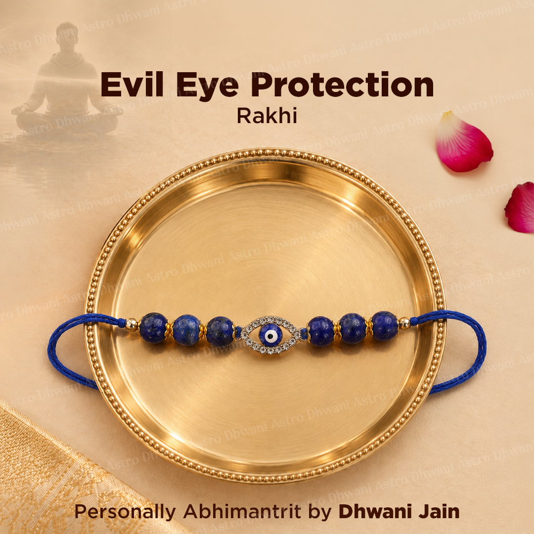 A blue and gold evil eye rakhi bracelet is displayed on a round gold-colored brass plate. The bracelet features lapis lazuli beads, a central evil eye motif with a silver-tone border and blue-and-evil eye, and blue cord ends.