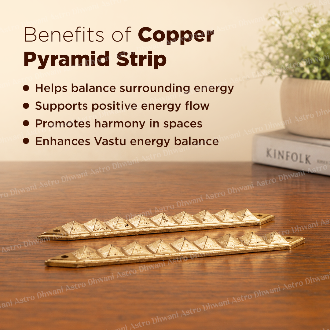 Two brass pyramid strip charms displayed on a wooden table with text overlays detailing their purported benefits, alongside a potted plant and a book in the background.Vastu Copper Pyramid Strip | Energy Balancing Strip for Home & Office | Vastu Remedy