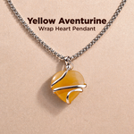 Yellow aventurine wrap heart pendant on a chain against a beige background
